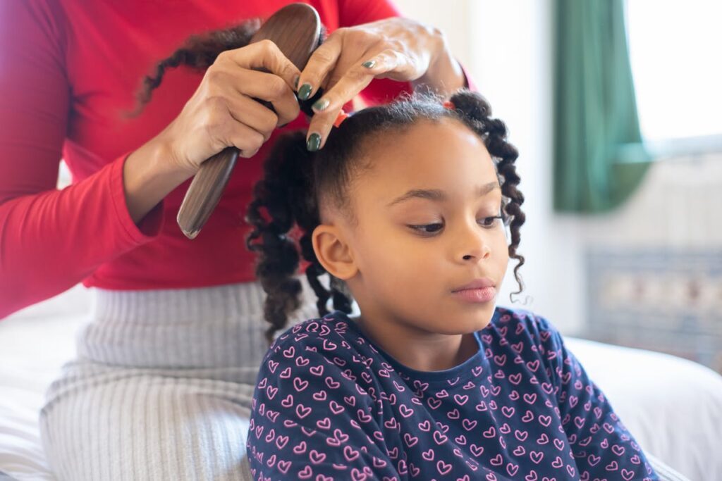 pexels-photo-6948104 A mother lovingly styles her daughter's hair, creating braided pigtails in a warm indoor setting.
