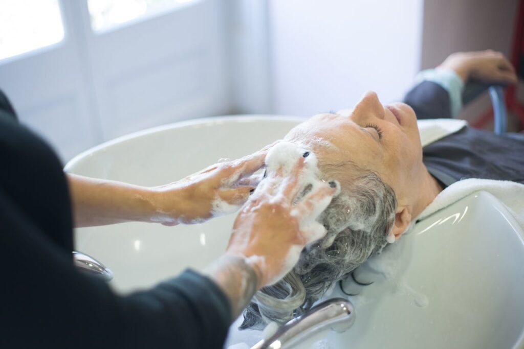 pexels-photo-8834067 Close-up of senior woman getting hair washed with foam at salon sink, enjoying the pampering session.